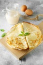 Russian pancakes served with mint leaves and ingredients - milk and eggs in front of grey background Royalty Free Stock Photo