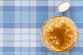 Russian pancakes with sour cream on checker tablecloth Royalty Free Stock Photo