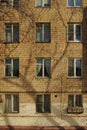 Russian panel house and windows of different apartments. Shadow from trees on house, winter landscape. Gas yellow pipe