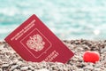 Russian passport and red heart in pebbles at beach on blue sea. Concept travel and vacation. Tourism and relaxation on ocean coast