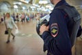 Russian police man in bulletproof vest at metro railway station Komsomolskaya with people in the background. Police is securing pe