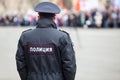 Russian policeman officer stands to opposite crowd with inscription Police on uniform jacket, Russia, copy space