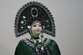 Russian porcelain woman doll in tranditional costume with green, silver jewellry decorated headdress called kokoshnik