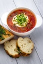 Russian red borscht with sour cream and greens in white bowl and pieces of bread on wooden background, table. Ukrainian cuisine Royalty Free Stock Photo