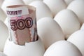 Russian ruble banknote in empty egg shell among white chicken eggs in cardboard tray closeup