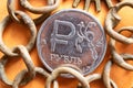 Old scratched Russian ruble coin and rusty chain on orange background