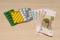 Russian rubles and several packs of medicines on a wooden table