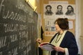 Russian rural school teacher wrote on chalkboard in classroom.