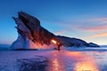 Russian Siberian fiery landscape. Sunrise at Lake Baikal. Silhouette of a man with a torch on the background of a rock.