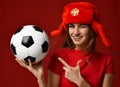 Russian style fan sport woman player in red uniform and ear-flap hat hold soccer ball celebrating happy smiling Royalty Free Stock Photo