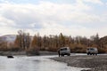 Russian SUVs near a mountain stream. Autumn landscape in the Altai Mountains.