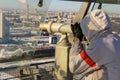 A russian tourist standing at viewpoint and looking at spyglass on panoramic view of the city.