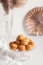 Russian traditional homemade cookies Nuts with condensed milk on glass stand on background of paper decor and reeds in vase White