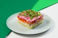 Russian traditional layered vegetable Shuba salad with fish fillet. Herring fish under fur coat on colorful green background