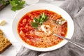 Russian traditional vegetable soup, borscht with sour cream and parsley in a white plate, spoon, on a gray napkin on a white Royalty Free Stock Photo