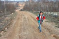 Russian village girl goes to school on a dirt road.