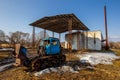 An old broken tractor stands against a brick boiler room in a Russian village. Royalty Free Stock Photo