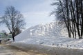 Russian winter. Huge snowhill and black trees without leaves.