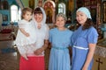 Russian women before toddler baptism are in church, godmother with goddaughter, mother with teenager daughter, indoor portrait