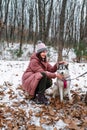 Russian young girl clung to Siberian husky lovingly against winter background in forest