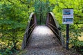 A rust colored iron bridge with a brown wooden footpath covered in fallen leaves over the silky brown waters of the Chattahoochee