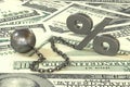 Rust iron ball and chain with the cuff hanging percent symbol on dollars banknotes background. Royalty Free Stock Photo