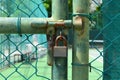 Rust lock at old green wire mesh fence in front of tennis court Royalty Free Stock Photo