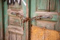 Rusted chain and curtains closed on an old rotten Green wooden door Royalty Free Stock Photo