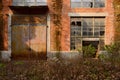 Rusted door and broken windows of deserted 1970s` red brick workshop