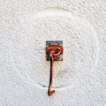 Rusted door hook with round trace on white wall