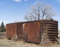 Rusted freight cargo train car abandoned in a field has old weeds and wood nearby. Royalty Free Stock Photo