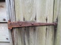 Rusted hinge and square nails on weathered wood