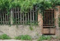 Rusted iron gate in an ancient brick and stone wall with wooden picket fence Royalty Free Stock Photo