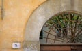 Rusted iron grate set in arched doorway with address on plaster wall Royalty Free Stock Photo