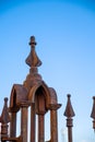 Rusted iron, ornamental gate post with clear blue sky in background