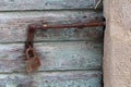 Rusted metal latch mounted on wooden boards doors locked with partially rusted padlock surrounded with concrete frame wall Royalty Free Stock Photo