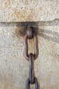 Rusted metal links of a chain anchored to a block of stone Royalty Free Stock Photo