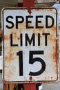 Rusted metal speed limit sign affixed to a tall metal pole in a rural area