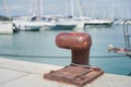 Rusted mooring bollard with sailing boat in background Royalty Free Stock Photo