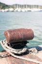 Rusted mooring bollard with sailing boat in background Royalty Free Stock Photo