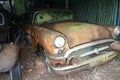 Rusted oldtimer car in old scruffy garage. Broken rust-covered vehicle. Brown and green tarnished Mercedes Benz