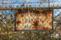 Rusted over danger sign left forgotten along steel fence in front of an abandoned factory