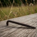 A rusted, pointed iron spike with a blunt hook end is positioned on a weathered Royalty Free Stock Photo