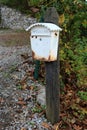 Rusted white mailbox on wooden pole