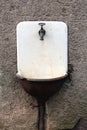 Rusted white vintage outdoor garden wash basin sink with retro spigot faucet on side of old dilapidated family house side wall Royalty Free Stock Photo
