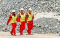 Conveyor belt transporting Platinum ore for processing with mining safety inspectors checking for damage