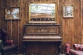 A rustic antique piano with a mirror above and a weathered wooden wall