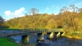 Rustic autumn scene of a stone bridge arching over the Wharfe River. Royalty Free Stock Photo