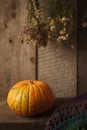 A rustic autumn still life with pumpkin, dry heral flowers and woolen scarf on a wooden surface. Thanksgiving, coutryside And Fall