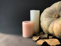 A rustic autumn still life. Pumpkin with golden leaves and a candles, illuminated by bright sunlight Royalty Free Stock Photo